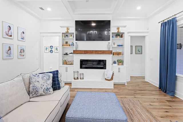 living room featuring a fireplace, coffered ceiling, ornamental molding, and light wood-type flooring