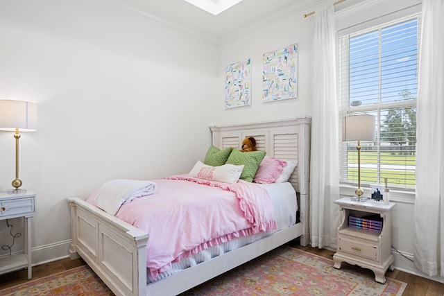 bedroom with crown molding, baseboards, wood finished floors, and multiple windows