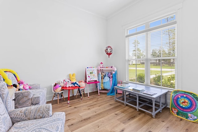 rec room featuring a healthy amount of sunlight, wood finished floors, and crown molding