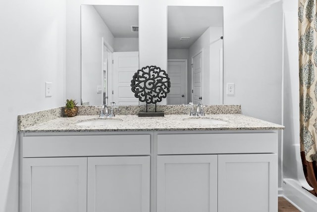 bathroom featuring double vanity, visible vents, and a sink