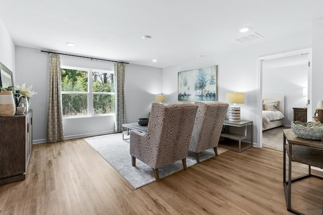 living area with light wood-style floors, visible vents, and baseboards