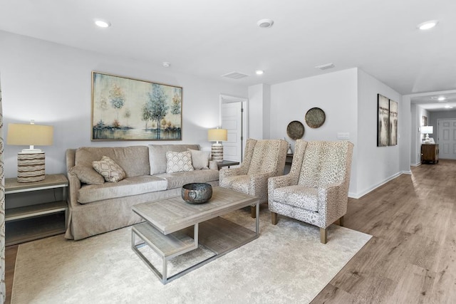 living room with recessed lighting, visible vents, baseboards, and wood finished floors