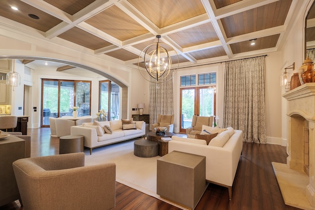 living room featuring dark hardwood / wood-style flooring, coffered ceiling, crown molding, beam ceiling, and a notable chandelier