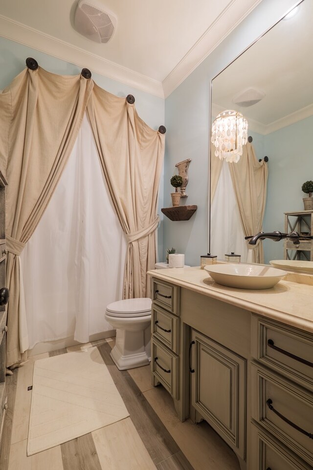 bathroom with wood-type flooring, vanity, toilet, and crown molding