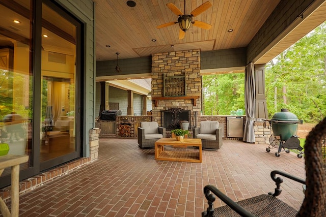 view of patio / terrace featuring an outdoor stone fireplace, ceiling fan, a grill, and an outdoor kitchen