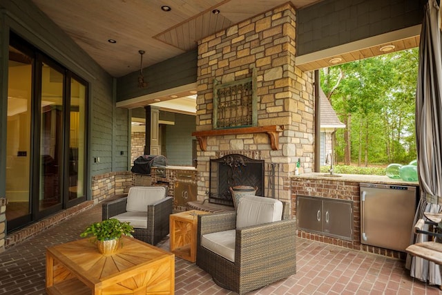 view of patio / terrace featuring an outdoor stone fireplace and sink