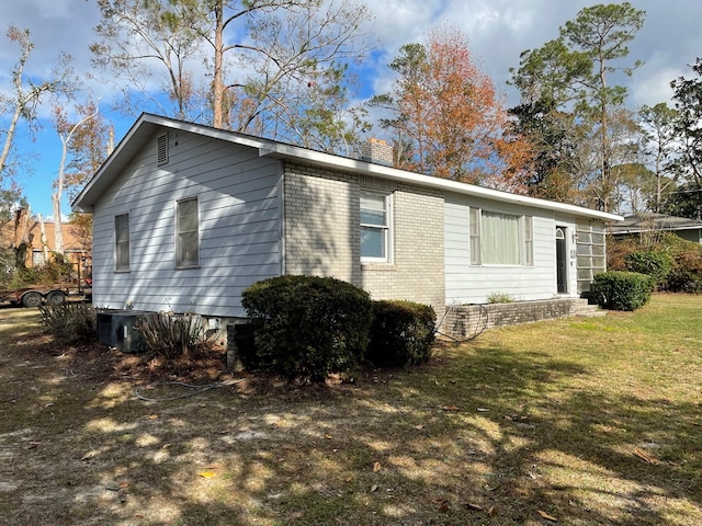 view of side of home featuring central AC unit and a yard