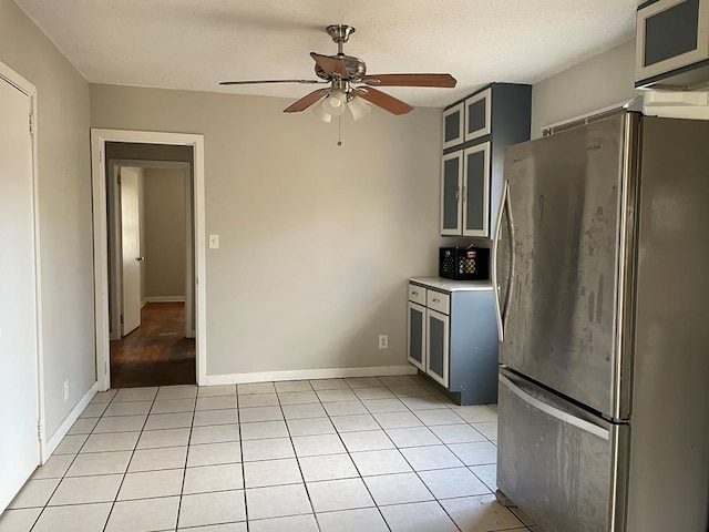 kitchen with stainless steel refrigerator, ceiling fan, light tile patterned floors, and a textured ceiling