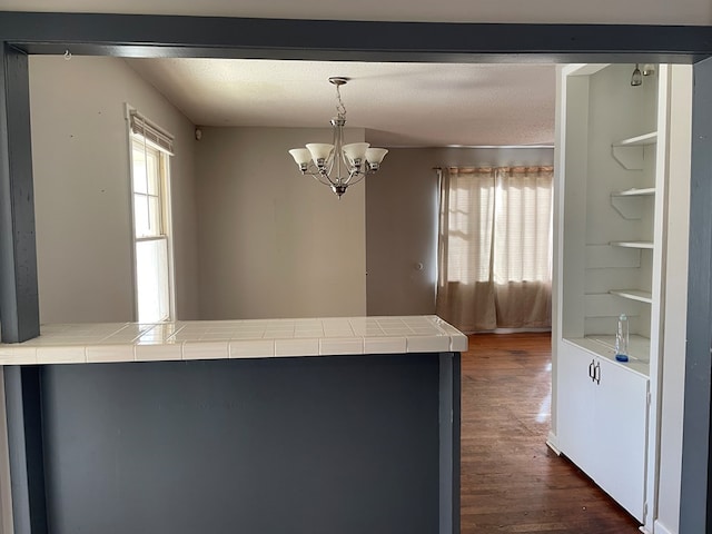 kitchen featuring dark hardwood / wood-style flooring, a chandelier, tile counters, and hanging light fixtures