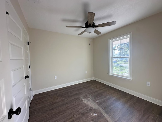 empty room with a textured ceiling, ceiling fan, and dark hardwood / wood-style floors