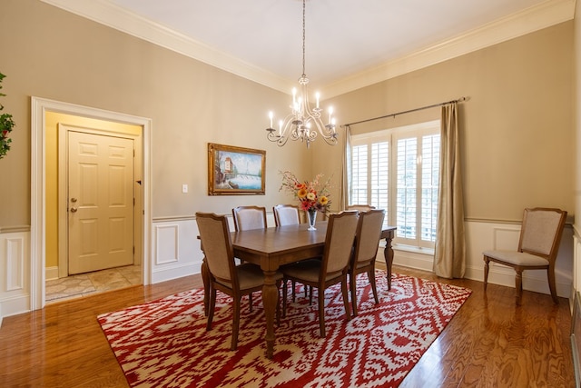 dining room featuring ornamental molding, wood finished floors, a chandelier, and wainscoting