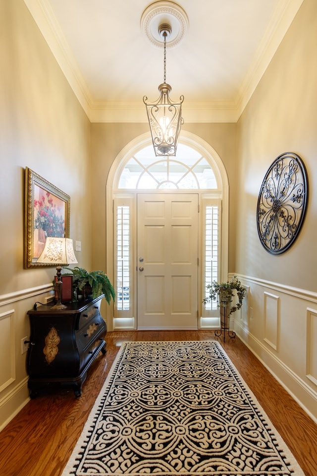 entrance foyer featuring ornamental molding, wood finished floors, and wainscoting