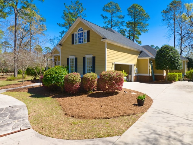 view of side of home featuring concrete driveway and a garage
