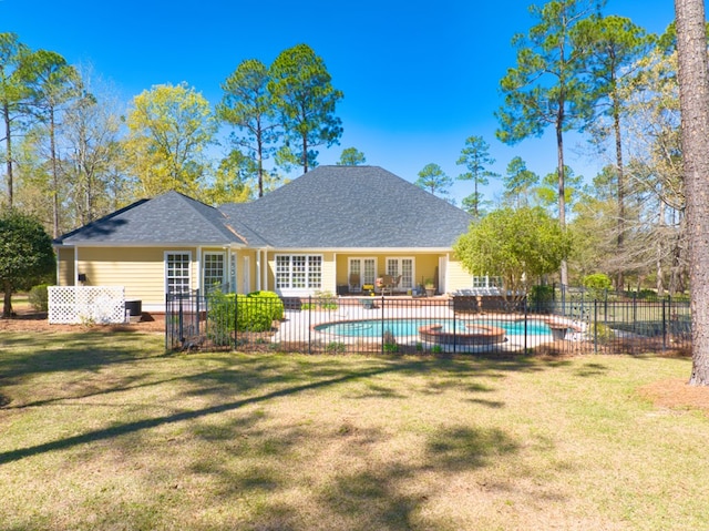 rear view of house with fence, roof with shingles, a lawn, a fenced in pool, and a patio area