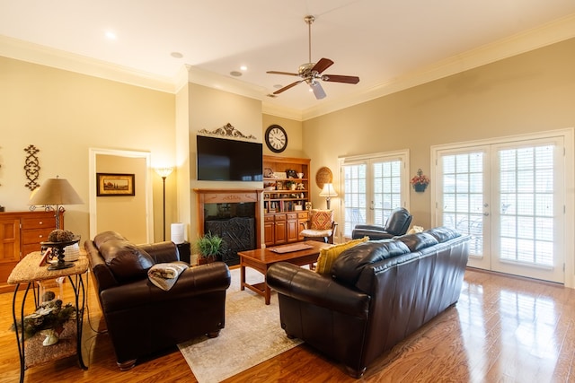 living area featuring crown molding, a fireplace, ceiling fan, wood finished floors, and recessed lighting