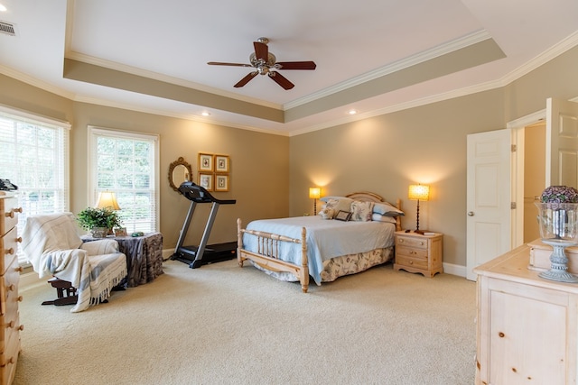 bedroom featuring visible vents, baseboards, ornamental molding, a tray ceiling, and light colored carpet