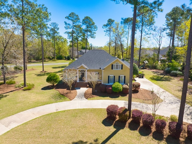 view of front of house featuring roof with shingles, curved driveway, and a front yard