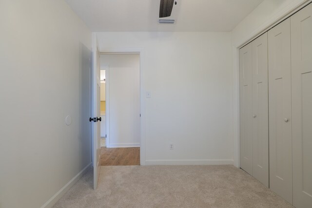 unfurnished bedroom featuring ceiling fan, a closet, and light colored carpet