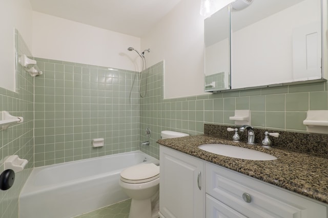 full bathroom featuring toilet, vanity, tiled shower / bath combo, and tile walls