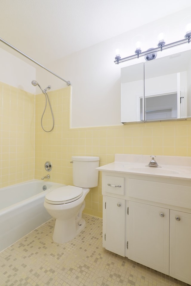 full bathroom featuring tile patterned floors, toilet, vanity, tile walls, and tiled shower / bath