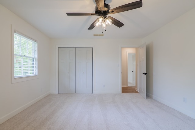 unfurnished bedroom featuring ceiling fan, a closet, and light colored carpet