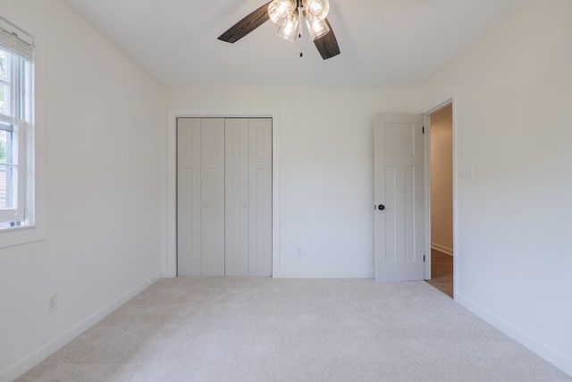 unfurnished bedroom with ceiling fan, light colored carpet, and a closet