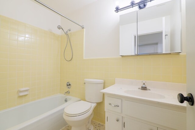 full bathroom with tile patterned floors, vanity, tile walls, toilet, and tiled shower / bath