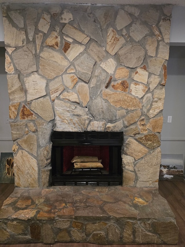 room details with hardwood / wood-style floors and a stone fireplace