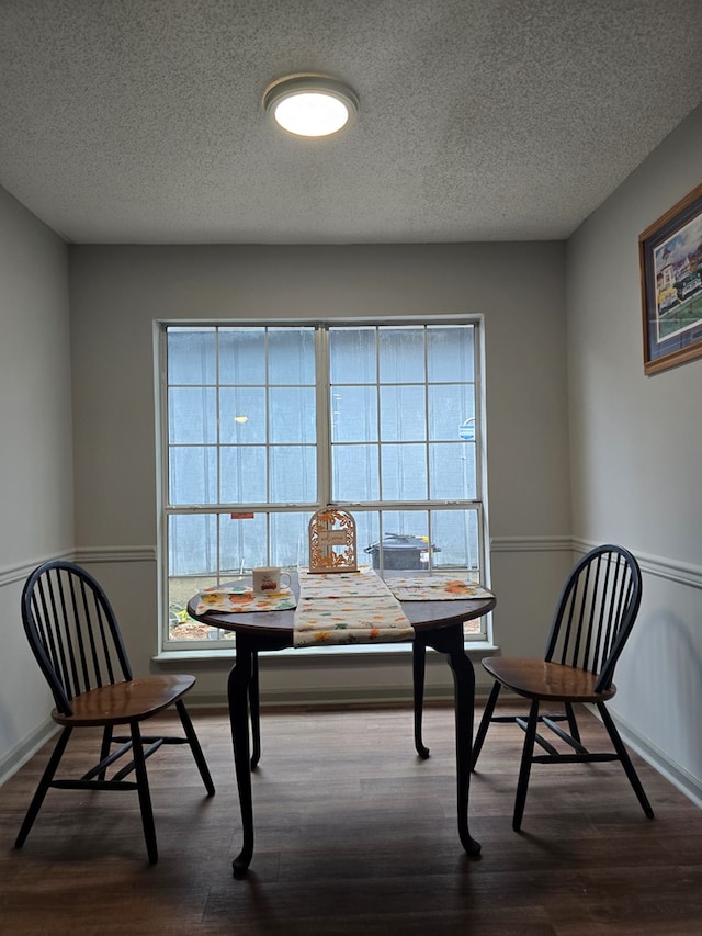 dining area featuring wood-type flooring and a textured ceiling