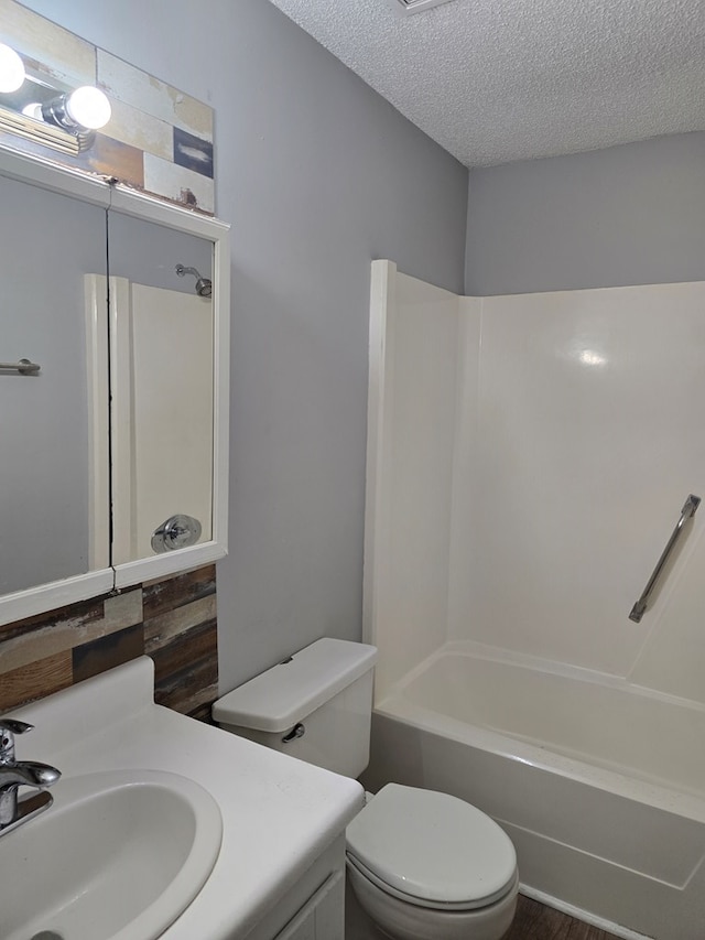 full bathroom featuring vanity, toilet, a textured ceiling, and bathing tub / shower combination