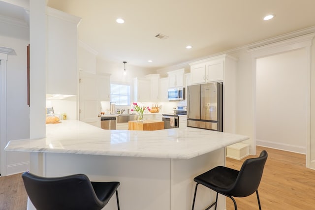 kitchen featuring a peninsula, visible vents, appliances with stainless steel finishes, light wood finished floors, and crown molding