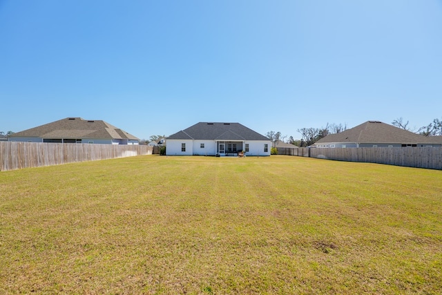 rear view of property with a yard and a fenced backyard