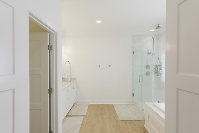 bathroom featuring wood finished floors, vanity, baseboards, ornamental molding, and a shower stall