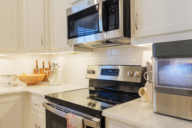 kitchen with stainless steel appliances, light countertops, white cabinetry, and backsplash