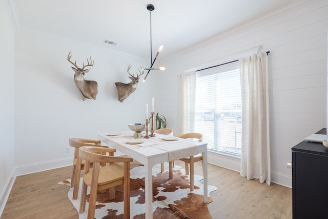 dining space with light wood-style flooring, visible vents, baseboards, and ornamental molding