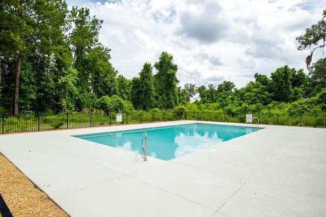 pool with a patio area and fence