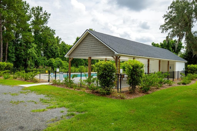 view of property's community with a pool, a yard, and fence