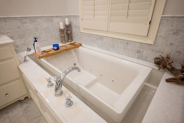 793 Lake Laurie Dr, Valdosta, GA 31605 - bathroom featuring a tub with jets, marble finish floor, and tile walls