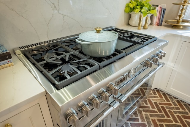 793 Lake Laurie Dr, Valdosta, GA 31605 - room details featuring decorative backsplash, white cabinets, high end stainless steel range, and light stone counters
