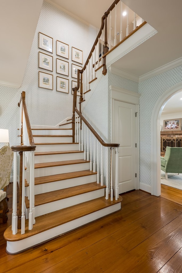 793 Lake Laurie Dr, Valdosta, GA 31605 - staircase featuring baseboards, ornamental molding, wallpapered walls, arched walkways, and hardwood / wood-style floors