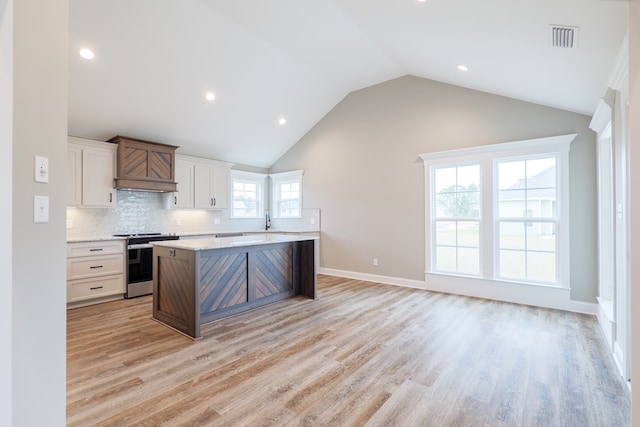 144 Audrey Ln, Hahira, GA 31632 - kitchen with stainless steel electric range, a center island, a sink, lofted ceiling, and light wood-type flooring