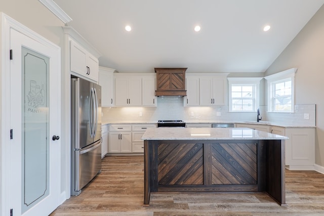 144 Audrey Ln, Hahira, GA 31632 - kitchen featuring appliances with stainless steel finishes, a sink, premium range hood, tasteful backsplash, and white cabinetry