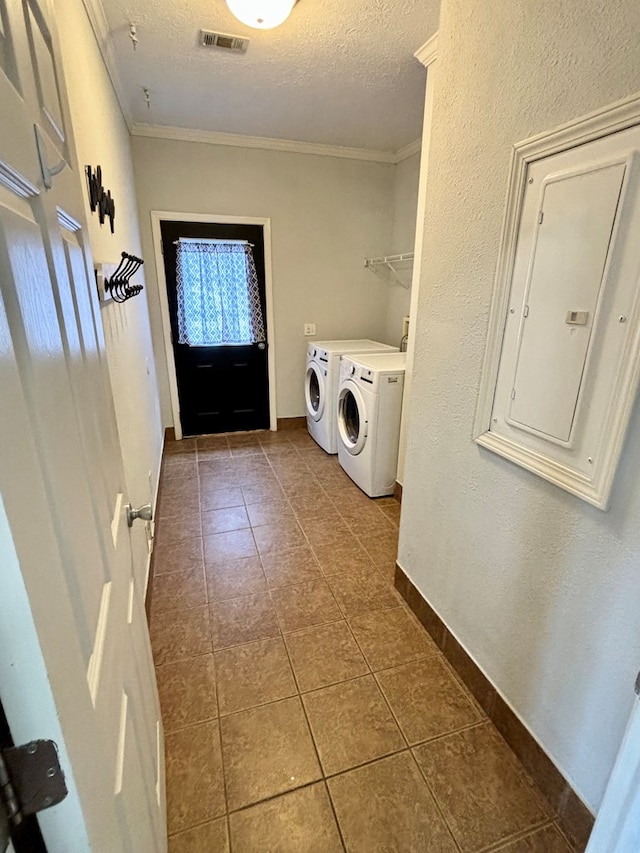 laundry room with electric panel, dark tile patterned flooring, crown molding, a textured ceiling, and washing machine and clothes dryer