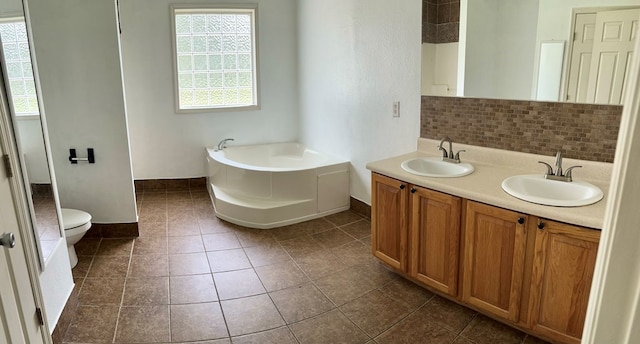 bathroom with vanity, a bath, tile patterned floors, decorative backsplash, and toilet