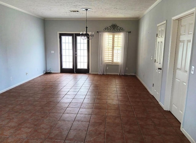 empty room with french doors, dark tile patterned flooring, ornamental molding, a textured ceiling, and a chandelier