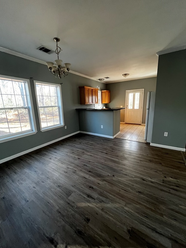 unfurnished living room with dark wood-type flooring, crown molding, and a notable chandelier