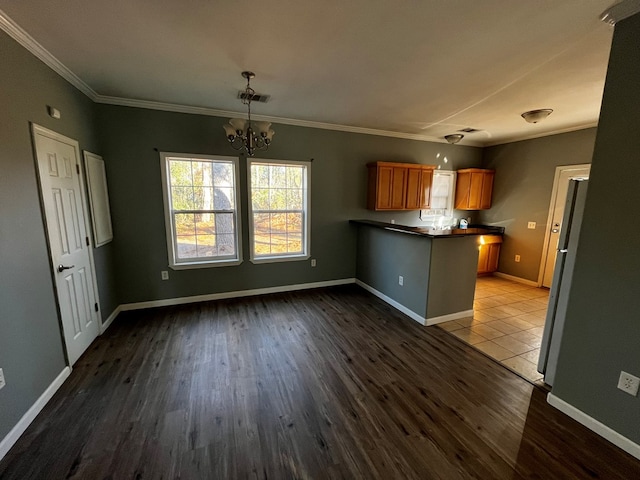 kitchen featuring decorative light fixtures, dark wood-type flooring, crown molding, and kitchen peninsula