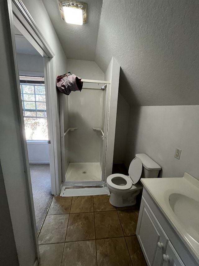 bathroom with a textured ceiling, lofted ceiling, tile patterned floors, vanity, and toilet