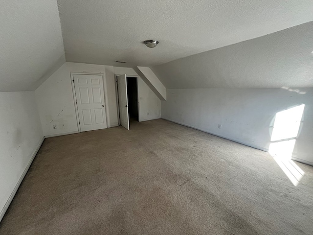 additional living space featuring carpet, vaulted ceiling, and a textured ceiling