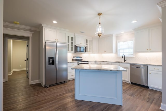 kitchen with appliances with stainless steel finishes, pendant lighting, white cabinetry, and glass insert cabinets